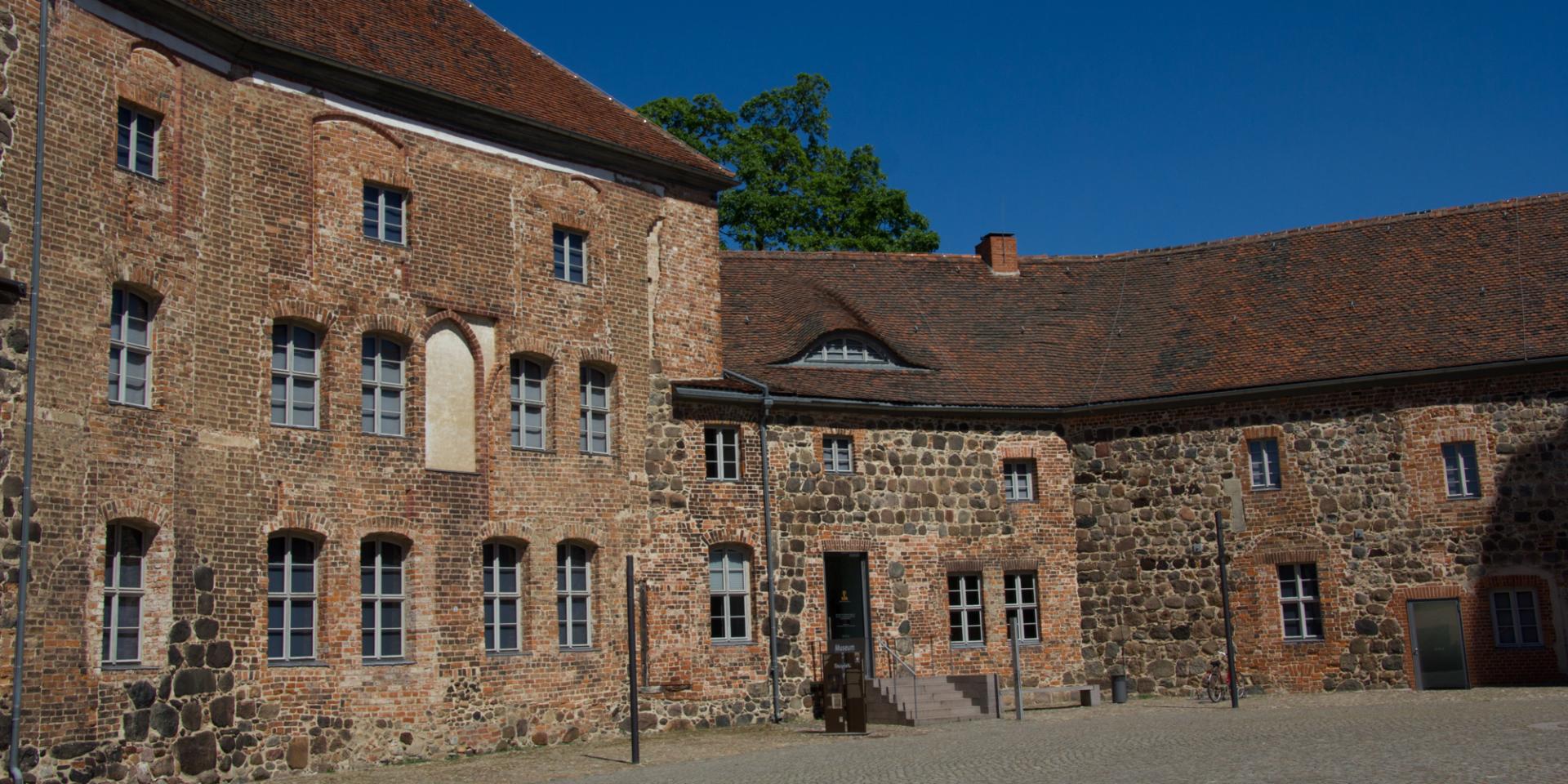 Historische Häuserfassade aus roten Back- und braunen Feldsteinen vor blauem HImmel