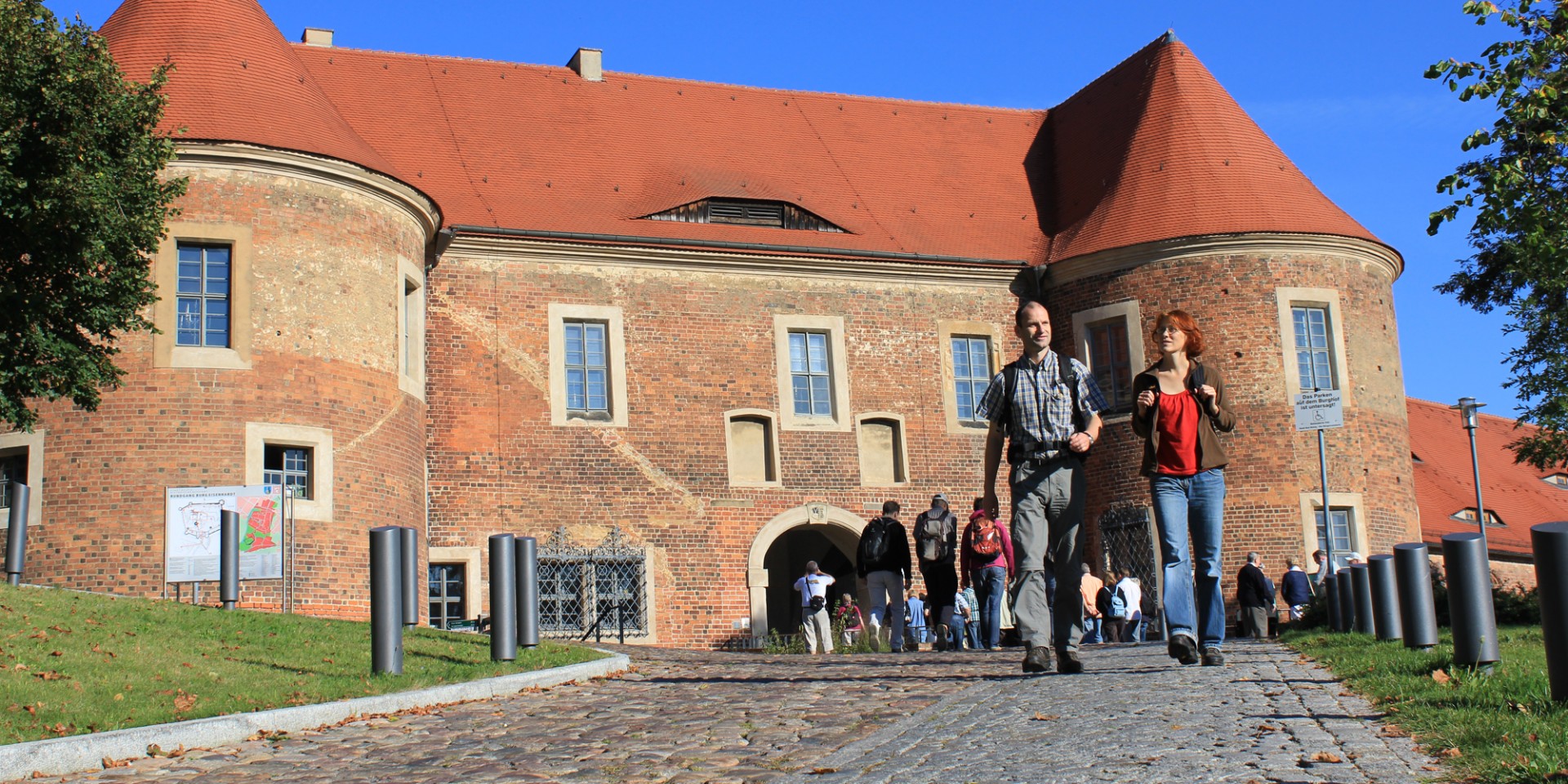 Ein Paar wandert die Auffahrt vor der Burg Eisenhardt in Bad Belzig herunter