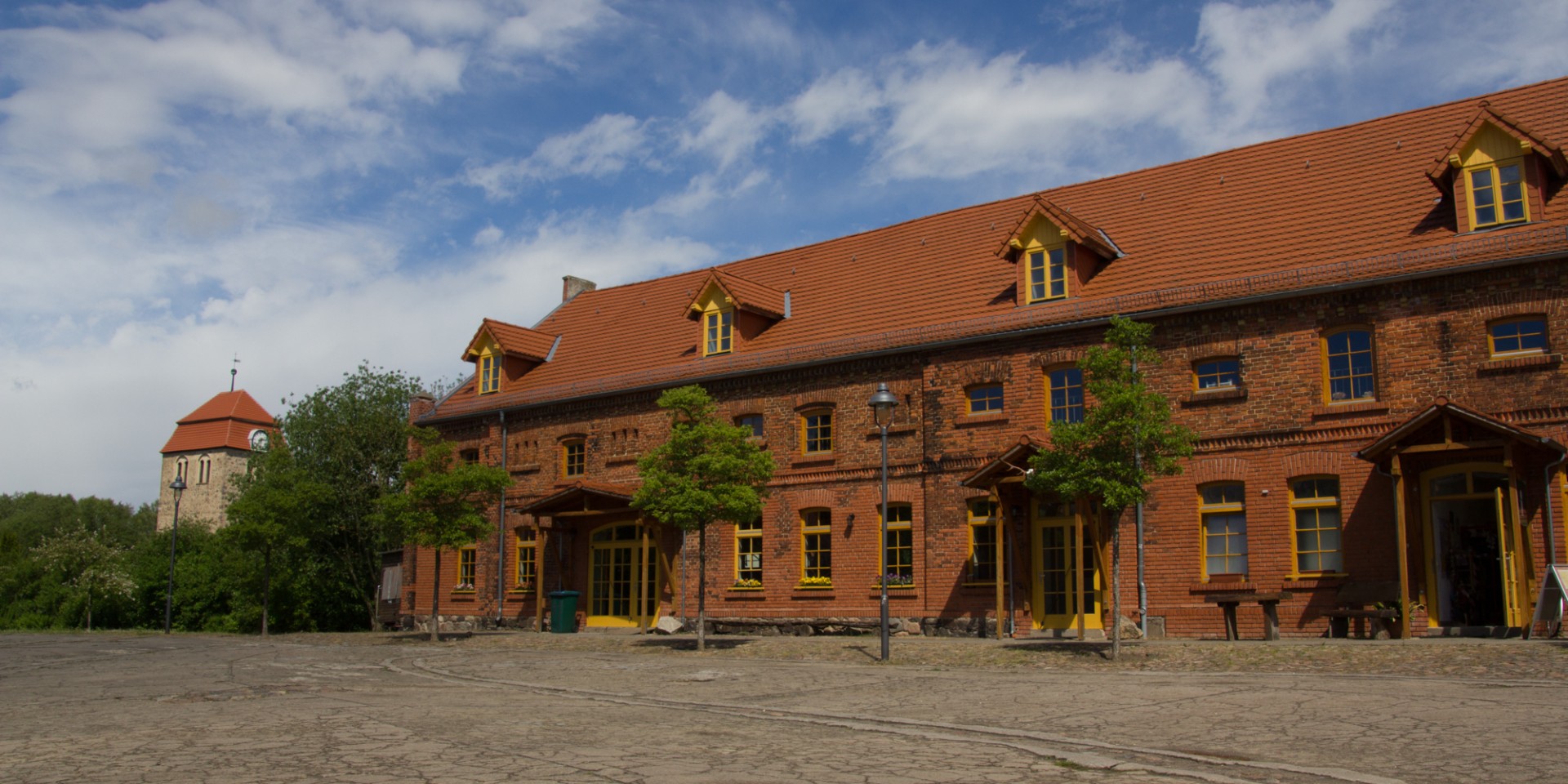 Rotes Backsteingebäude vor blau-weiß gemustertem Himmel