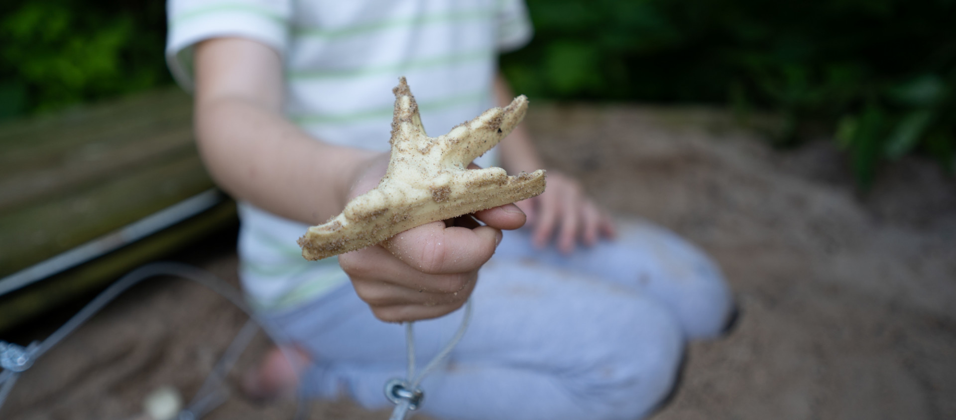 Ein Kind hält den Stempel einer Tierspur in die Kamera