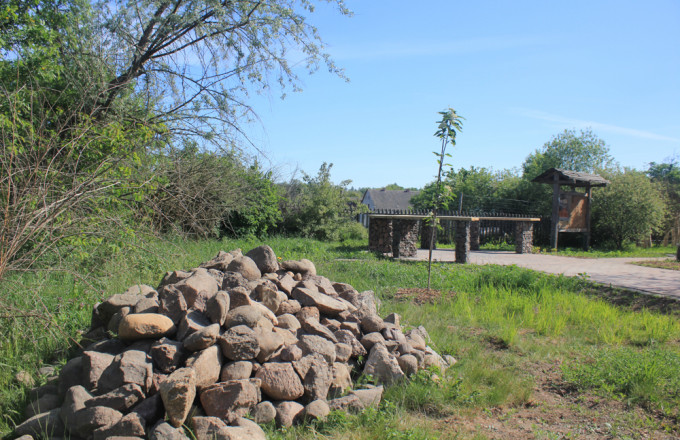 Feldsteine zum Lesesteinhaufen aufgeschichtet, im Hintergrund ist ein großer Tisch und eine Lehmwand für  Insekten zu erkennen