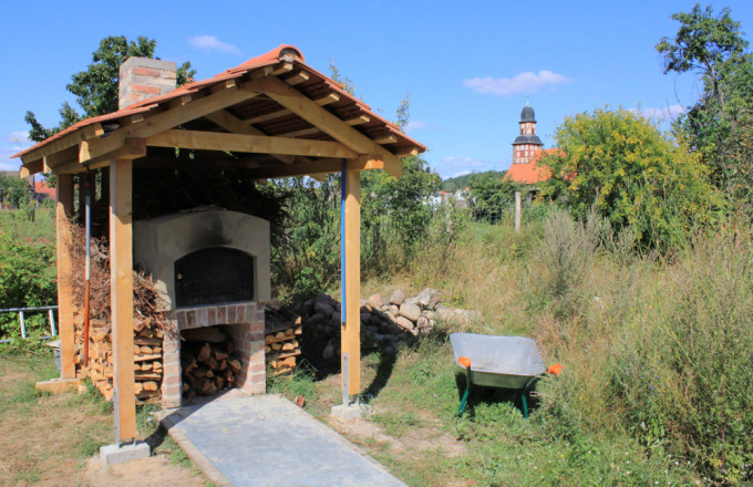 Lehmbackofen mit Holzständer-Ziegeldach vor der Dorfkirche Raben