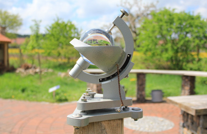 Sonnenschein-Autograph, bei dem die Sonne in einer Glaskugel gebündelt wird und Spuren in ein Papier brennt