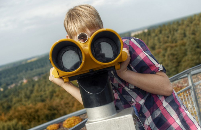 Ein Junge schaut durch ein Fernglas auf dem Turm der Burg Rabenstein