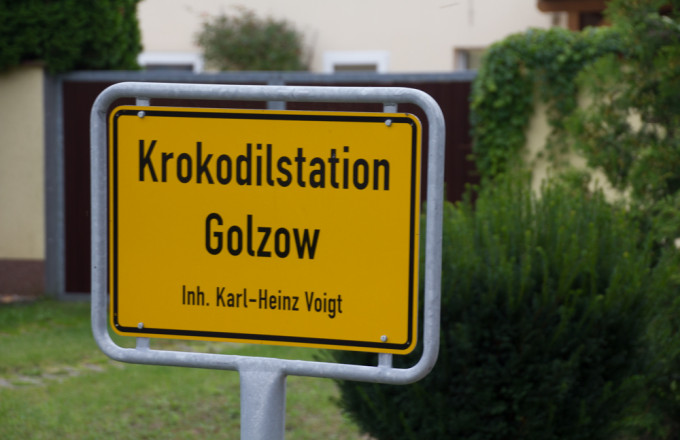 Gelbes Schild wie ein Ortseingangsschild, auf dem Krokodilstation Golzow steht