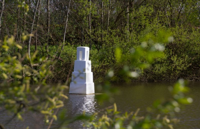 Eine weiße Skulptur schwimmt auf einem Teich