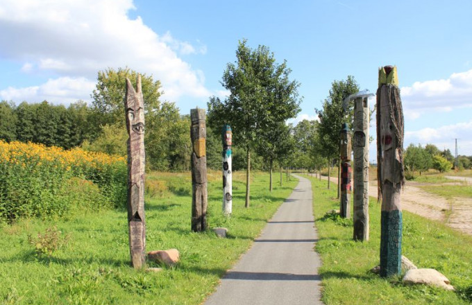 Als Gesichter gestaltete Holzstämme säumen einen Weg