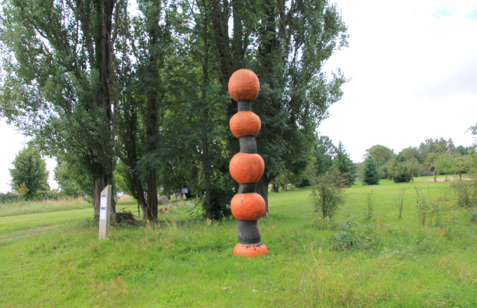 Holz-Kunstwerk aus übereinander aufgefädelten orangefarbenen großen Kugeln