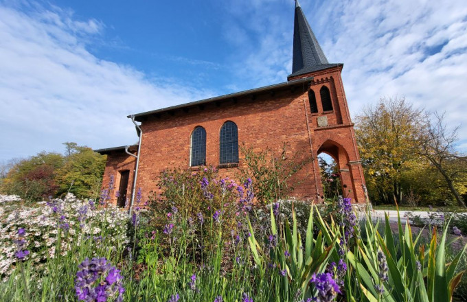 Blüten vor einer kleinen roten Backsteinkirche