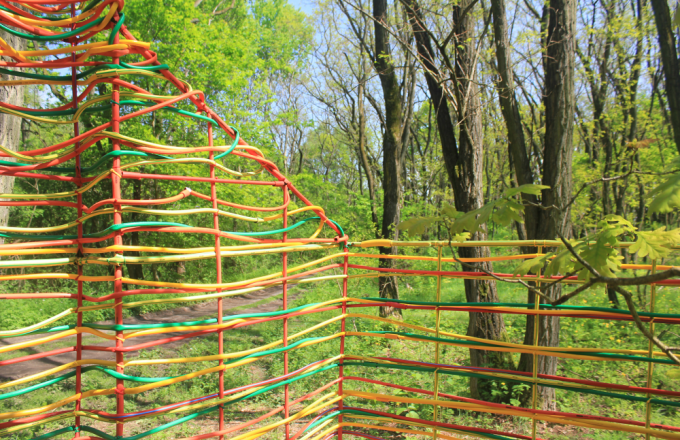 Gelbe, rote und grüne Gartenschläuche bilden Hauswände im Wald