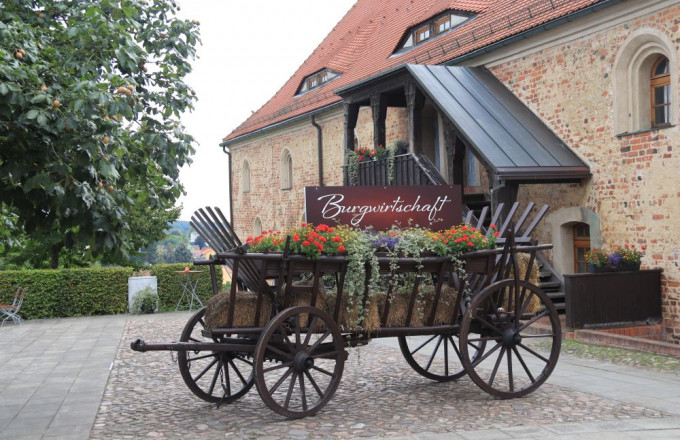 Ein alter Holzwagen mit Blumen dekoriert und einem Schil Burgwirtschaft