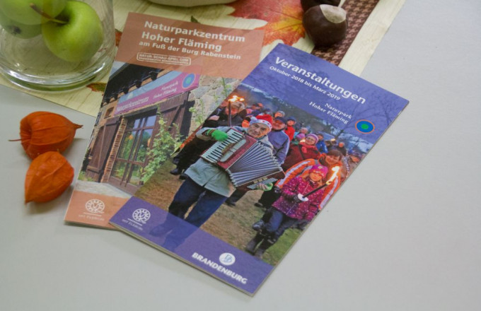 Zwei Faltblätter liegen auf einem Tisch.