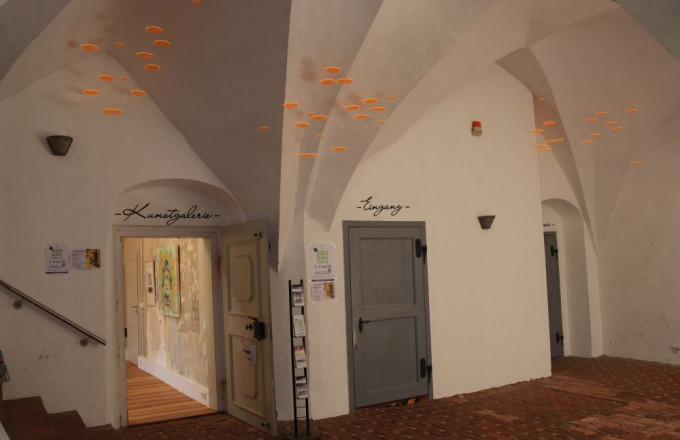 Eine offene Tür führt in einen Raum, in dem Bilder an der Wand hängen