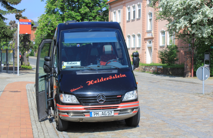 Ein Kleinbus mit geöffneter Tür trägt im Fenster das Schild Raben.