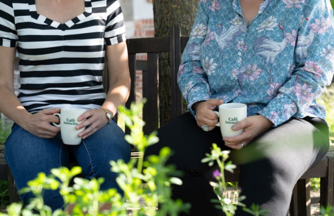 Zwei Menschen sitzen auf einer Bank mit Kaffeetassen in den Händen